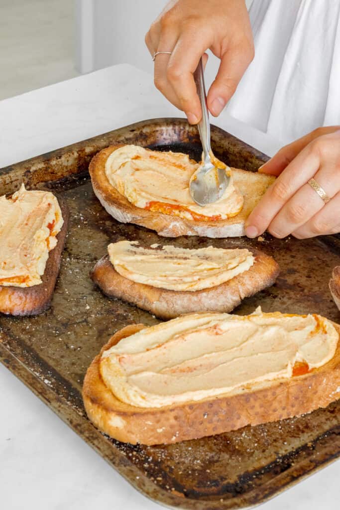 Spreading the hummus onto the sourdough toast.