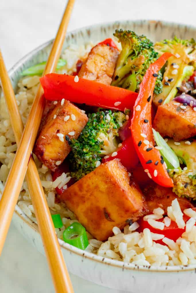 Close up of Crispy Tofu Hoisin Stir-fry in bowl with chopsticks. Vegan, GF & Healthy! Georgie Eats.