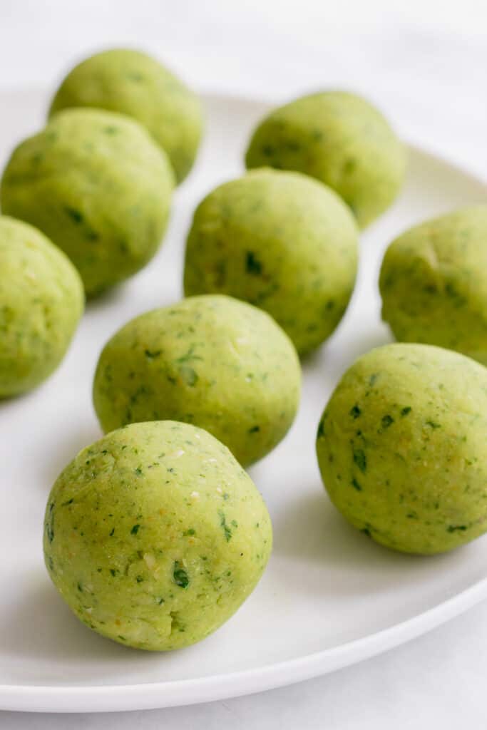 Balls of uncooked falafel on a plate.