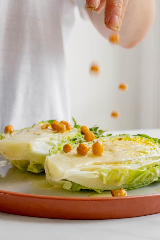 Sprinkling crispy chickpea croutons over the vegan Caesar Salad.