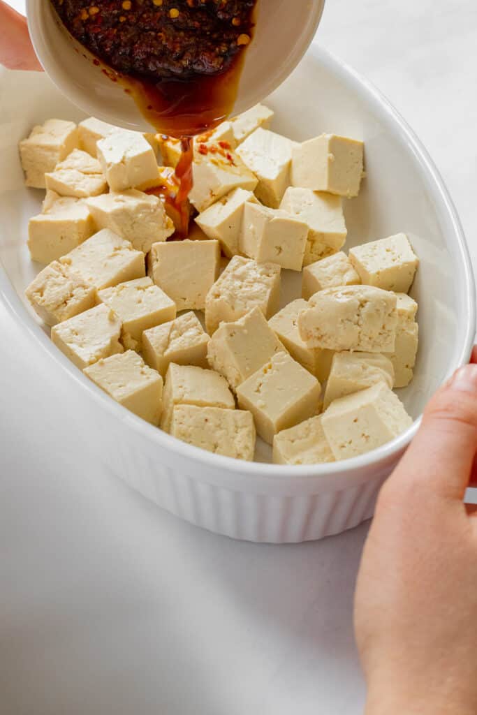 Pouring the marinade over chunks of tofu.