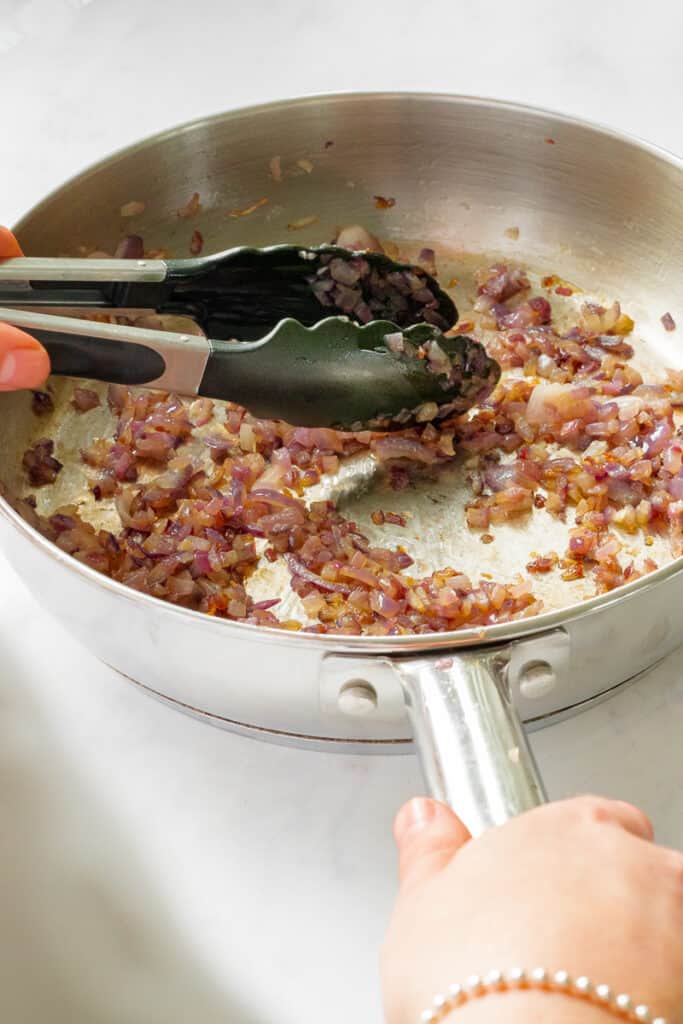 Frying the red onion in a pan.
