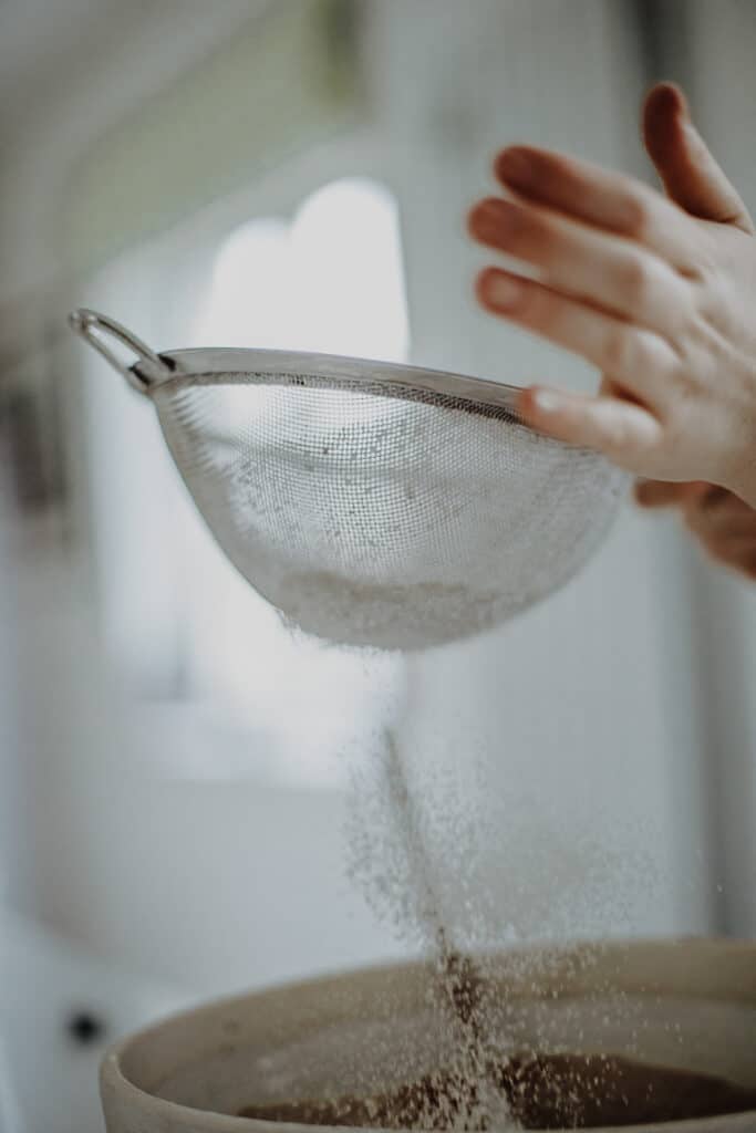 Sifting flour into a bowl.