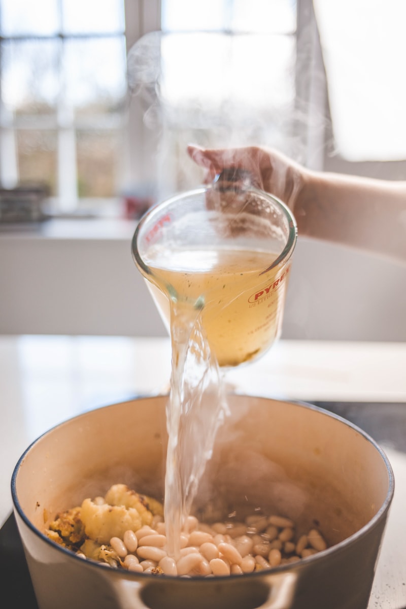 pouring stock into saucepan