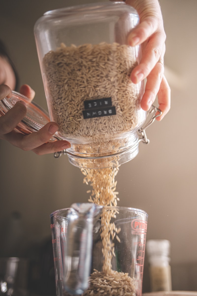 pouring brown rice into a measuring jug