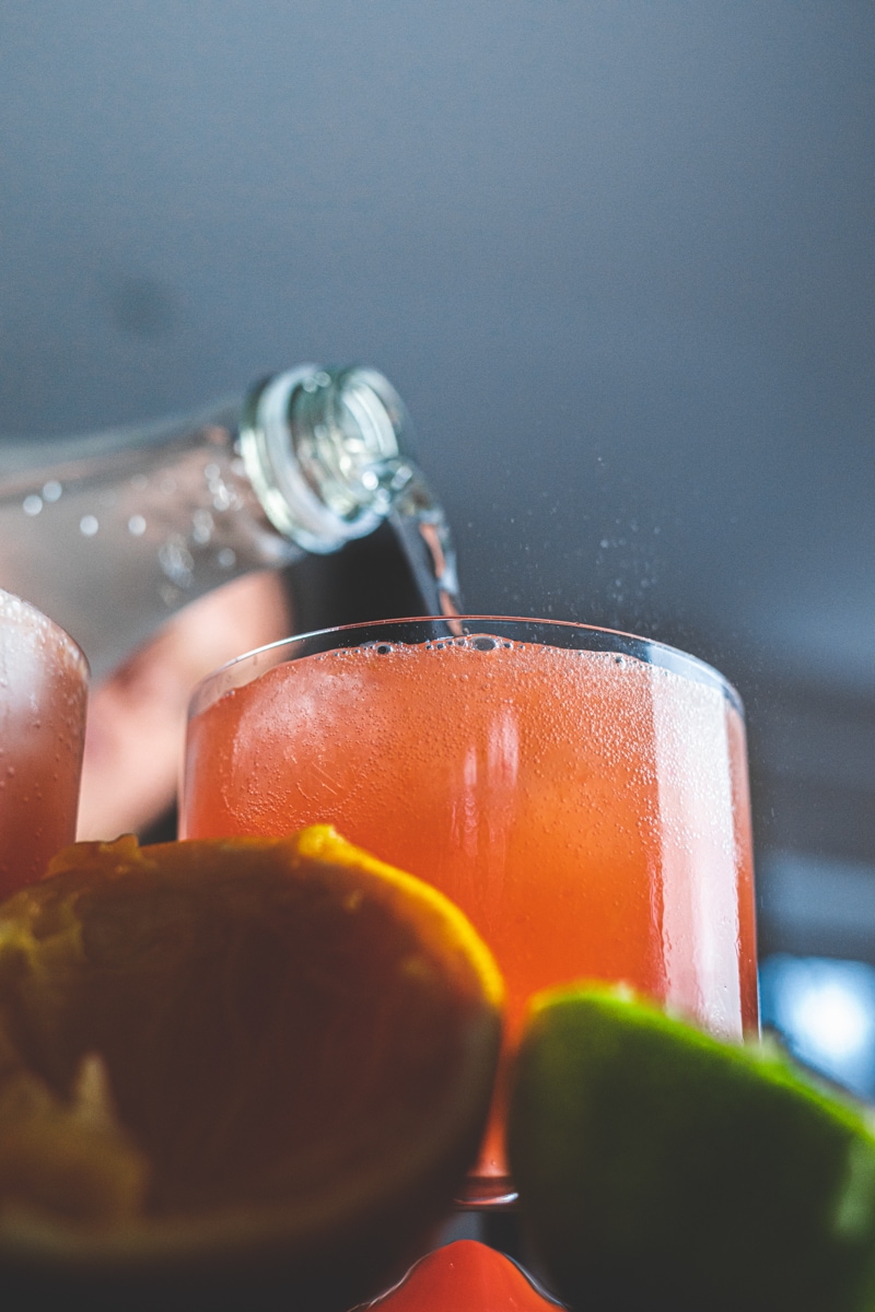 Pouring soda water into blood orange mocktail