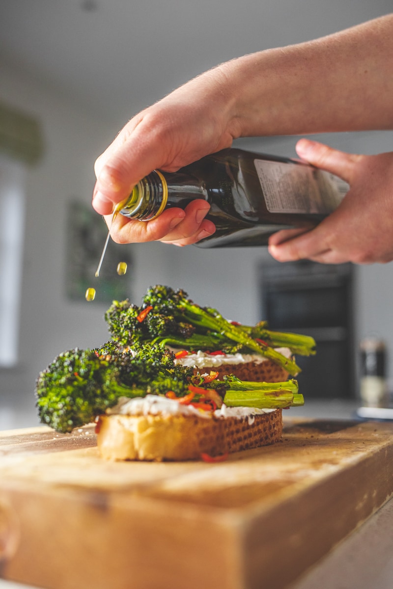 Drizzling olive oil over Purple Sprouting Broccoli on Toast - Georgie Eats