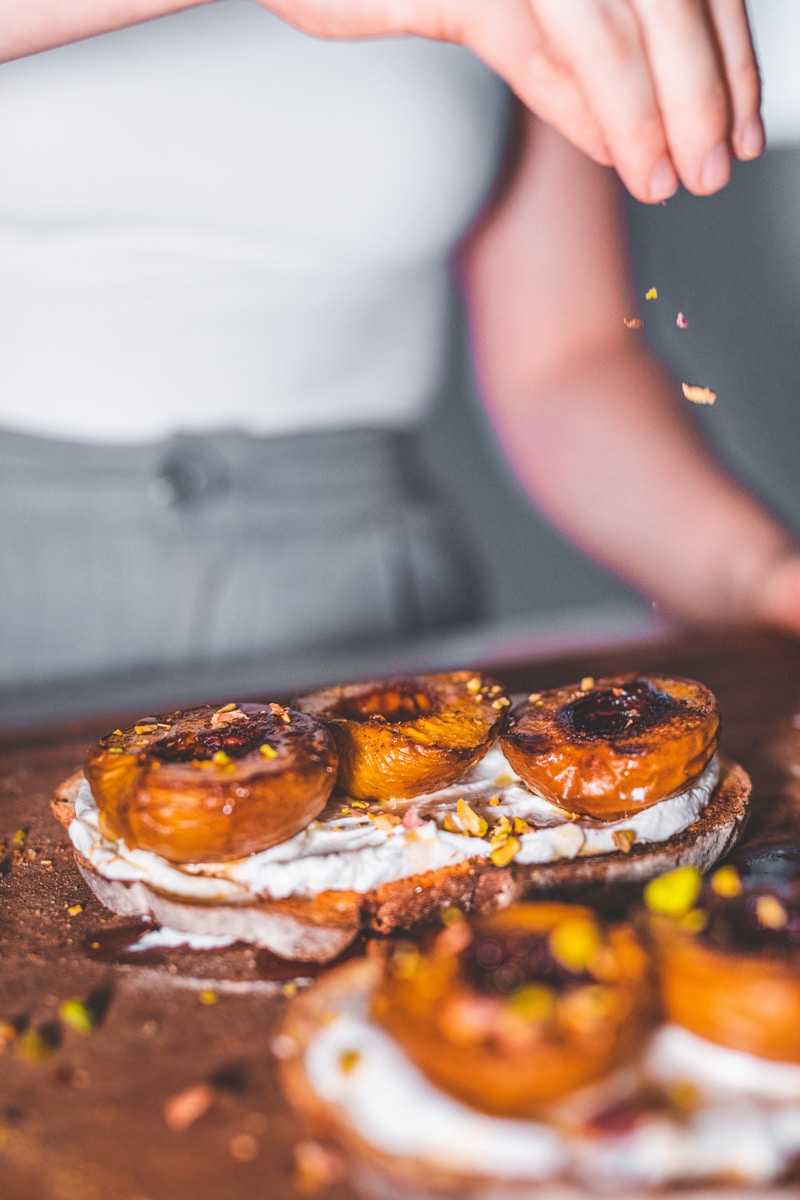 Sprinkling the Maple Roasted Peaches On Toast with Pistachios - Georgie Eats