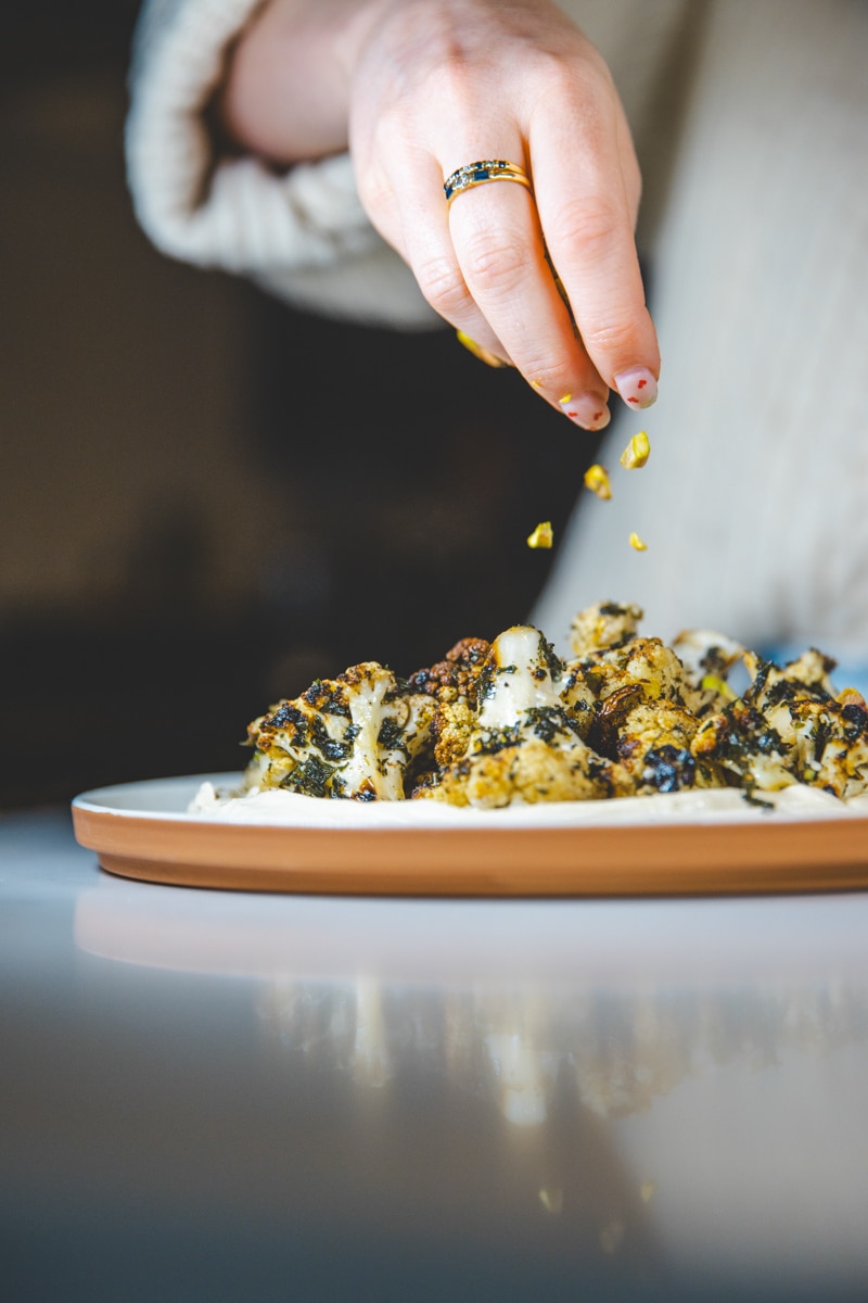 sprinkling pistachios on Marinated Cauliflower & Tofu Ricotta - Georgie Eats