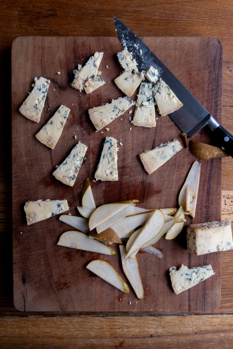 Slices of stilton and pear on a chopping board - Georgie Mullen